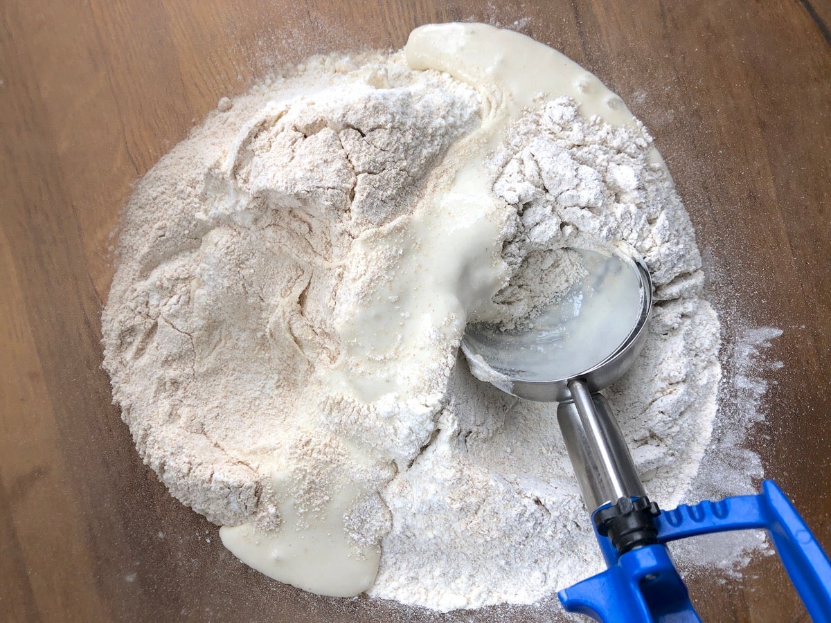 Starter added to a bowl of flours using a muffin scoop, pictured in the bowl.